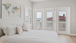 Un dormitorio con una cama grande, un mapa del mundo en la pared y vistas a un edificio a través de la ventana.