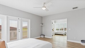 Un dormitorio con cama, ventilador de techo y vistas al exterior.