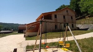 A rustic wooden building with a dirt path leading to a swing set in a grassy area. - Le Séchoir des acacias, 110m2 gîte "La Noyeraie" with heated swimming pool. (SAINT-LEON-SUR-VEZERE)