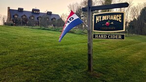 Een bord met 'Mt. Defiance Cider Barn', een vlag en een gebouw op de achtergrond.