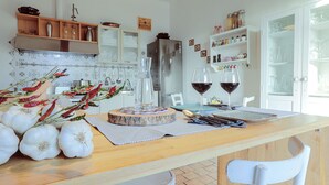 A kitchen with a wooden island, white chairs, and a refrigerator. - [VILLA ACQUAPIETRA FLORENCE⭐⭐⭐⭐⭐] Pool | Vineyards | Olive trees (San Casciano Val di Pesa)