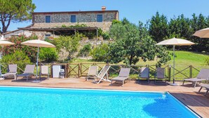 A pool area with lounge chairs and umbrellas, a stone building in the background, and a clear blue sky. - [VILLA ACQUAPIETRA FLORENCE⭐⭐⭐⭐⭐] Pool | Vineyards | Olive trees (San Casciano Val di Pesa)