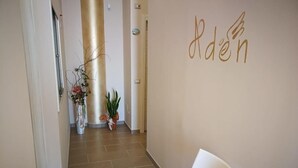 En hall med en vit stol, krukväxter och en vägg där ordet ”Rden” är skrivet.