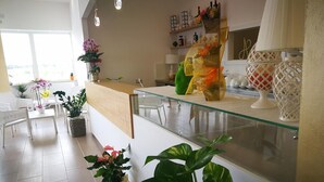Ett modernt receptionsområde med en glasvägg, krukväxter och en mängd olika dekorativa föremål på hyllor.