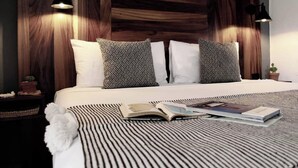 A modern bedroom with a wooden headboard, two patterned pillows, a striped rug, and a book on the bed.