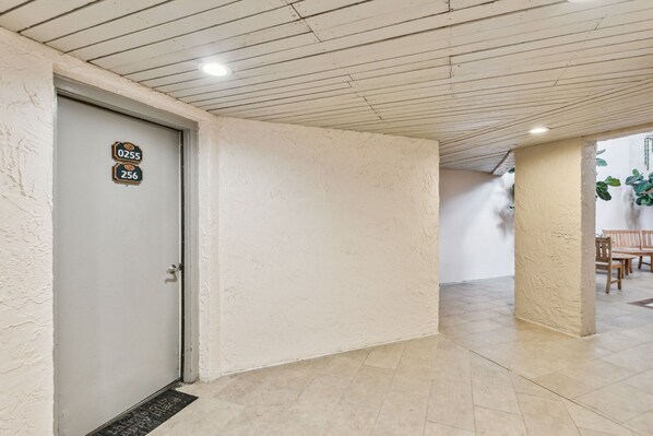 A hallway with a door marked 0255 and 256, leading to a room with a tiled floor and a ceiling with wooden beams.