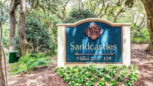 Señal para Sandcastles Villas 255-329, rodeada de árboles y vegetación.
