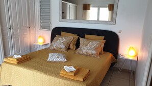 A neatly made bed with a quilted bedspread, two bedside lamps, and a mirror above the bed. - Villa JELUCA Beautiful and spacious villa with swimming pool (SAINT MARTIN)