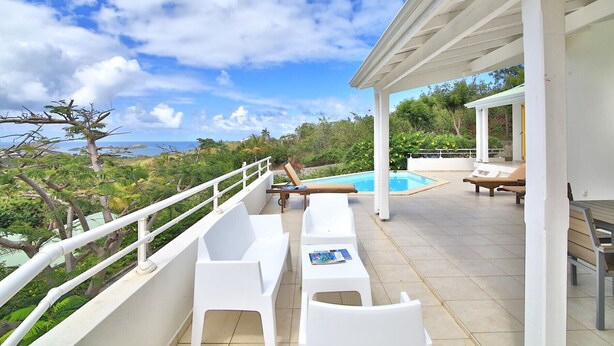 A covered outdoor area with a pool, white lounge chairs, and a view of the ocean. - Villa JELUCA Beautiful and spacious villa with swimming pool (SAINT MARTIN)