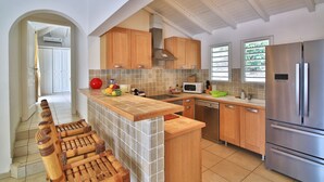 A modern kitchen with wooden cabinets, a built-in island, a stainless steel refrigerator, and a microwave. - Villa JELUCA Beautiful and spacious villa with swimming pool (SAINT MARTIN)