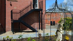 A brick building with a black metal staircase leading to a balcony. - Cockloft, Romantic Countryside Hideaway (Bishops Cannings)