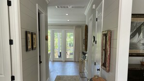 A hallway with a patterned rug, white walls, and a dark wooden cabinet.