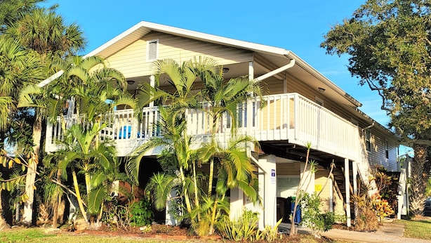 A two-story house with a covered porch and a garage. - New Modern Chic Suite Walkable Steps to Beach (Indian Rocks Beach)