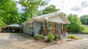 A single-story house with a porch, a covered outdoor seating area, and a gravel driveway.