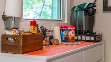 A kitchen counter with a coffee maker, coffee pods, and condiments.