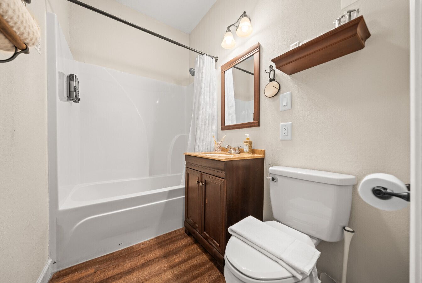 A bathroom with a bathtub, toilet, vanity, and a mirror.
