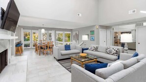 A spacious living room with a sofa set, a coffee table, and a dining area with chairs and a table.