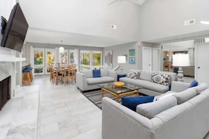A spacious living room with a sofa set, a coffee table, and a dining area with chairs and a table.