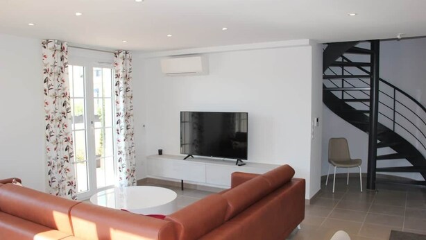 Una sala de estar moderna con un sofá, un televisor, una escalera y un sillón.