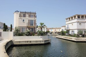 A canal with buildings on either side, a swan in the water, and a clear sky.
