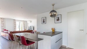 Una sala de estar moderna con comedor, un sofá, una mesa de centro y una isla de cocina.