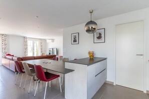 Una sala de estar moderna con comedor, un sofá, una mesa de centro y una isla de cocina.