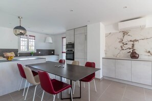 A modern kitchen with a dining table, red chairs, and a marble backsplash.