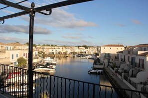 A marina with boats docked, a clear sky, and buildings with balconies.