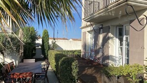 Un edificio residencial con balcón, mobiliario exterior y un jardín cuidado.
