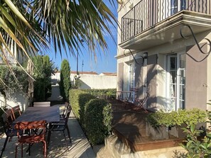 Un edificio residencial con balcón, mobiliario exterior y un jardín cuidado.