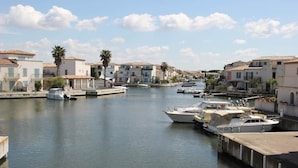 Un port de plaisance avec des bateaux amarrés, une eau calme et des bâtiments dotés de balcons le long de la rive.