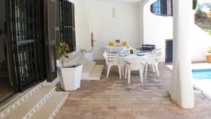 Ein möblierter Außenbereich mit Terrasse, Tisch, Stühlen, einem Topfpflanzen und einem Pool.