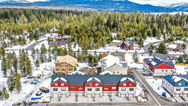Un quartier résidentiel avec des maisons, un immeuble en construction et une montagne boisée en arrière-plan.
