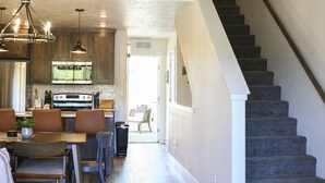 Une cuisine moderne avec un coin repas, un escalier et une vue sur l’extérieur.