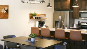 Une cuisine moderne avec des meubles en bois, un réfrigérateur en acier inoxydable et un coin bar équipé de tabourets.