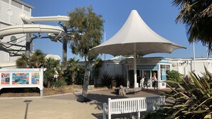 Area accoglienza per le vacanze con un ombrellone grande, una panchina e un cartello con la scritta 'Holiday Reception'.
