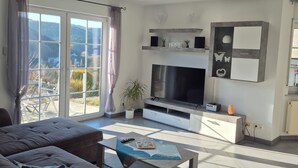Un salon avec un canapé, un téléviseur et une vue sur l’extérieur.
