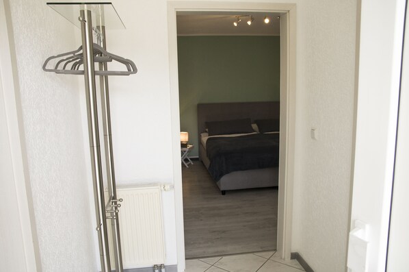 A bedroom with a bed, a nightstand, and a hanging shower curtain rod.