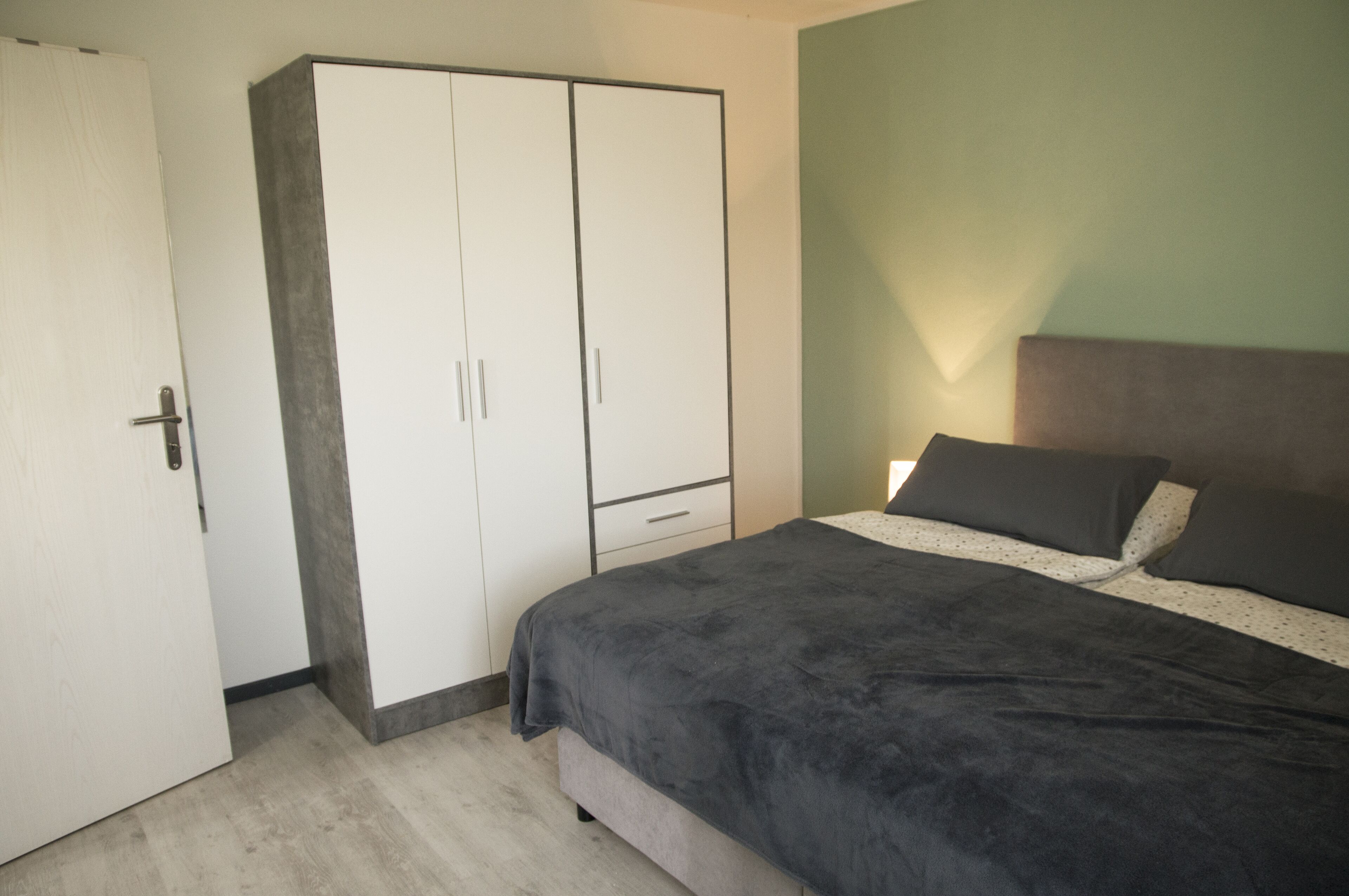 Een slaapkamer met een bed, een garderobe en een nachtkastje.