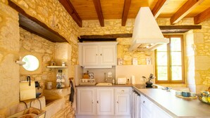 Une cuisine rustique avec des murs en pierre, des poutres en bois et des meubles blancs.