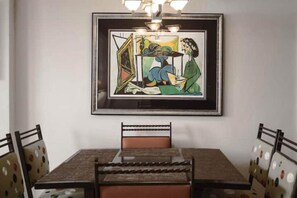 A dining area with a table and chairs, a framed artwork on the wall, and a chandelier. - Pool/Valet/TropicalOceanView 1brwithTerrace (Palm Beach)