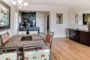 A dining area with a table and chairs, a kitchen in the background, and a hallway leading to another room. - Pool/Valet/TropicalOceanView 1brwithTerrace (Palm Beach)