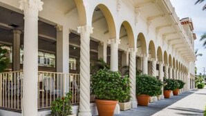 A building with a series of arches and columns, outdoor seating with potted plants, and a clear sky. - Pool/Valet/TropicalOceanView 1brwithTerrace (Palm Beach)