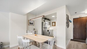 Una cucina moderna con mobili bianchi, un frigorifero in acciaio inossidabile e un tavolo da pranzo in legno con sedie bianche.
