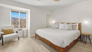 Una camera da letto con un letto, una sedia, un comodino, una lampada da tavolo e una ventola a soffitto.