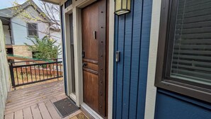 Una porta d'ingresso in legno con maniglia in metallo, un piccolo portico con ringhiera metallica e un tappetino di benvenuto.