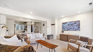 A modern living room with a sofa, armchair, coffee table, and a painting on the wall.