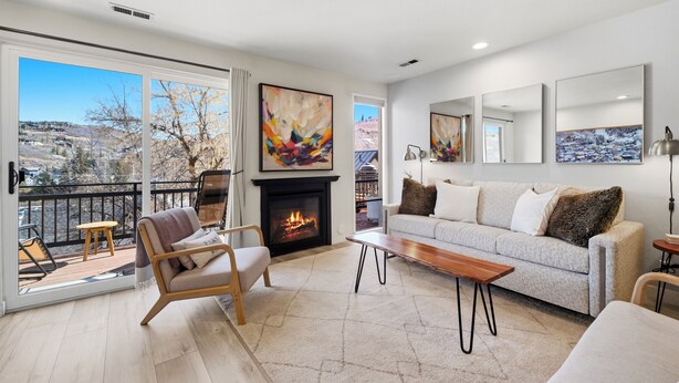A modern living room with a fireplace, a sofa, a chair, and a view of the outside.