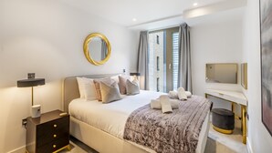 Una camera da letto moderna con un letto, un comodino, una lampada e un grande specchio.
