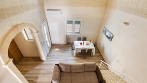 Un vaste espace de vie comprenant un grand canapé d’angle beige, une table à manger avec des chaises et un escalier.